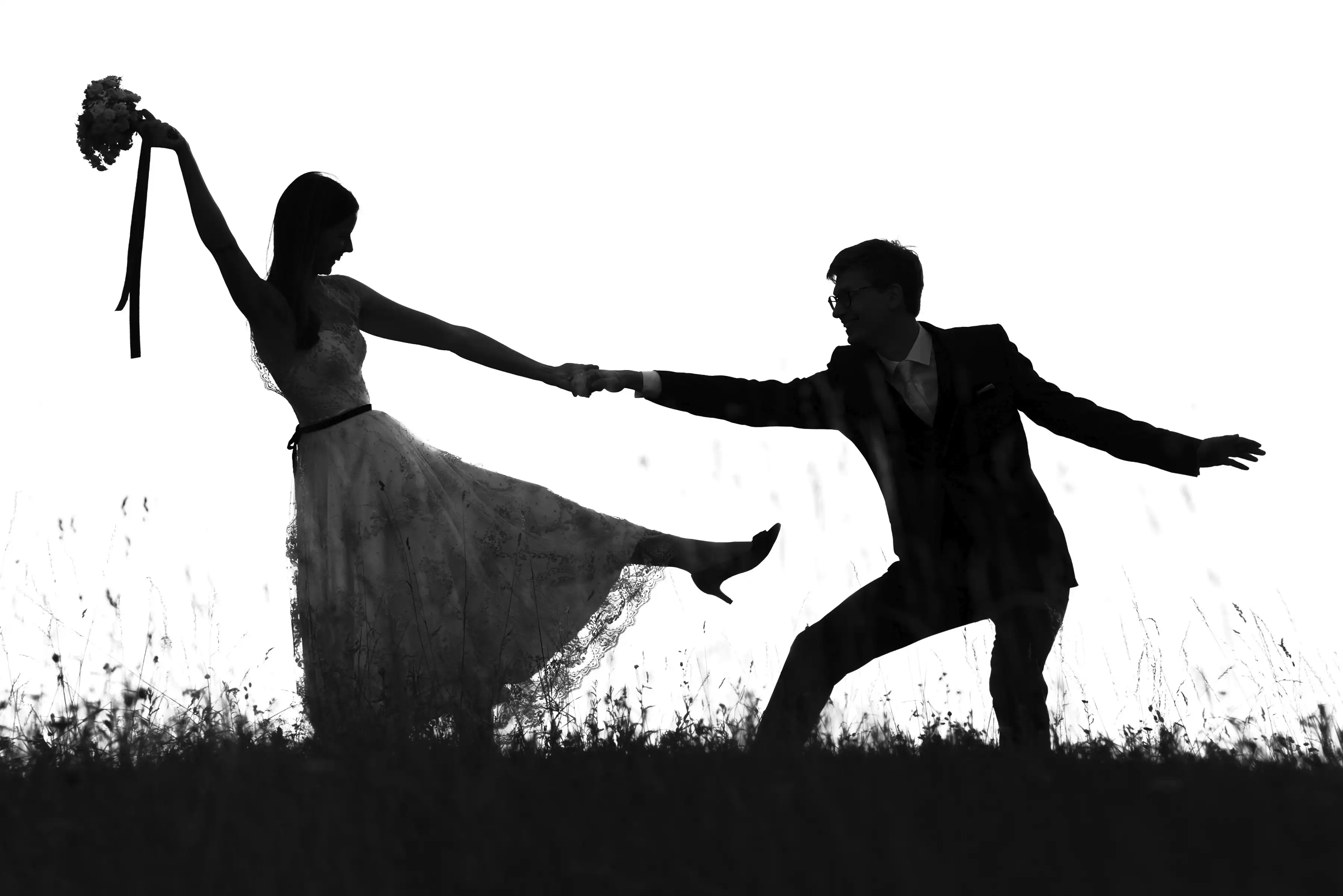 Silhouette eines tanzenden Hochzeitspaares auf einer Blumenwiese